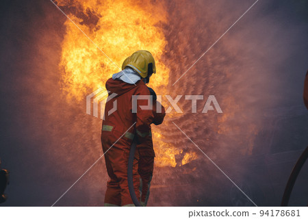 Firefighter Rescue training in fire fighting extinguisher. Firefighter fighting with flame using fire hose chemical water foam spray engine. Fireman wear hard hat, safety suit uniform for protection 94178681