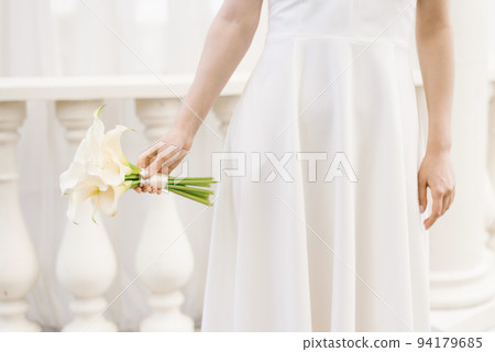 Delicate white bouquet of calla lilies in the hands of the bride at the wedding Delicate white bouquet of calla lilies in the hands of the bride at the wedding 94179685