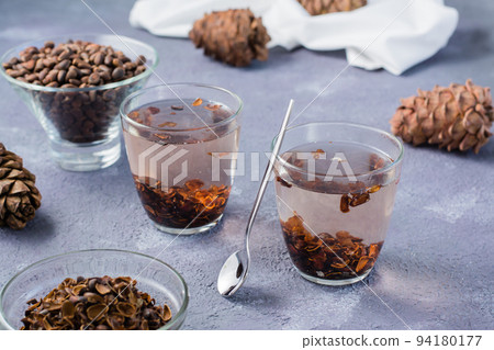 Infusion of pine nut shells in glasses and pine nuts on the table. Alternative medicine. 94180177