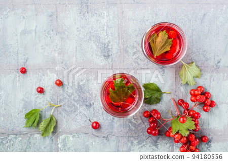 A decoction of ripe viburnum berries in transparent glasses and berries next to it on the table. Alternative medicine, vitamin nutrition and wellness. Top view 94180556
