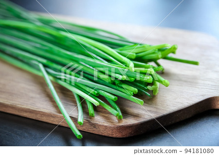 Bunch of chives on a wooden cutting board Bunch of chives on a wooden cutting board 94181080