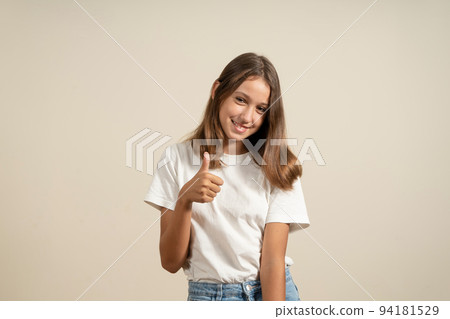 Teenager girl over isolated beige wall with thumb up because something good happened. Teenager girl over isolated beige wall with thumb up because something good happened. 94181529