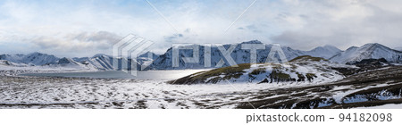 Season change in the Icelandic highlands.  Colorful Landmannalaugar mountains under snow cover in autumn. Frostastadavatn lake at the foot of the mountains. 94182098