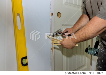 The hammer is used by one of the trim workers when installing interior doors in a new house 94183074