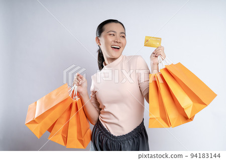 Asian woman happy smiling holding shopping bags and credit card isolated over white background. 94183144