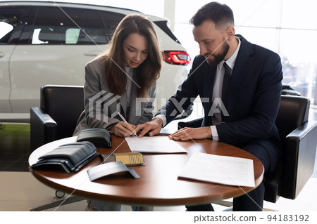 young woman and car sales manager sign a contract 94183192