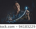 Asian woman pointing a growing virtual hologram of statistics, graph and chart. 94183229