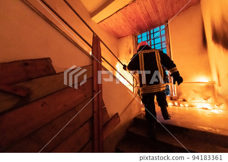 Brave Fireman going upstairs to save and rescue people in a Burning Building. Open fire and flame. Brave Fireman going upstairs to save and rescue people in a Burning Building. Open fire and flame. 94183361