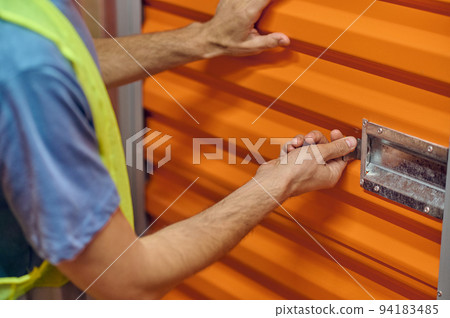Warehouse employee hands opening the old latch lock Warehouse employee hands opening the old latch lock 94183485