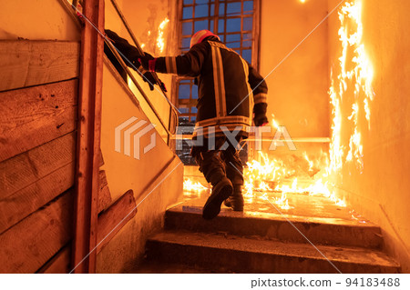 Brave Fireman going upstairs to save and rescue people in a Burning Building. Open fire and flame. 94183488