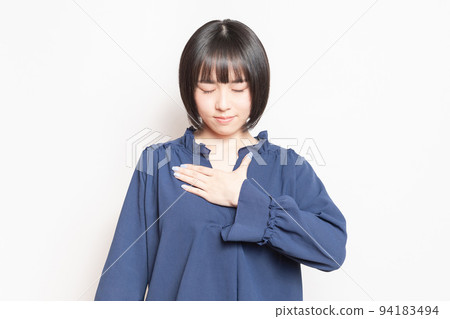Young woman with her hand on her chest in front of a white background Young woman with her hand on her chest in front of a white background 94183494