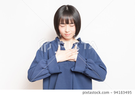 Young woman with her hand on her chest in front of a white background Young woman with her hand on her chest in front of a white background 94183495