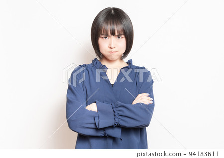Angry young woman standing in front of white background Angry young woman standing in front of white background 94183611