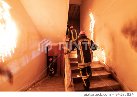 Brave Fireman going upstairs to save and rescue people in a Burning Building. Open fire and flame. Brave Fireman going upstairs to save and rescue people in a Burning Building. Open fire and flame. 94183824