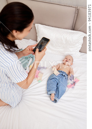Mother takes pictures of baby by smartphone Mother takes pictures of baby by smartphone 94183971