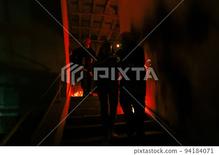 Brave Fireman Descends Stairs of a Burning Building and Holds Saved Girl in His Arms. Open fire and one Firefighter in the Background. 94184071
