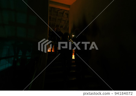 Brave Fireman Descends Stairs of a Burning Building and Holds Saved Girl in His Arms. Open fire and one Firefighter in the Background. 94184072