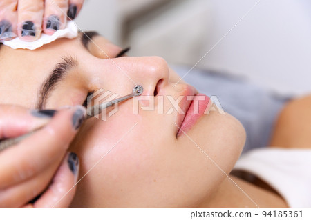 Closeup of hands making cleaning of skin. Young beautiful girl during cosmetic procedures in the beautician's office. Spa, beauty, skin care, wellness, cosmetics 94185361