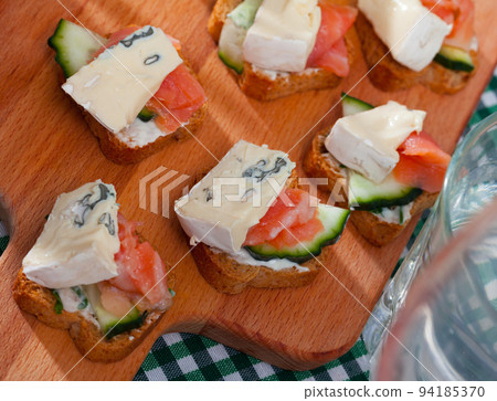 Toasted bread slices with salmon and cambozola Toasted bread slices with salmon and cambozola 94185370