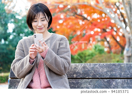 一位年輕女子在秋葉公園裡使用智能手機 94185371