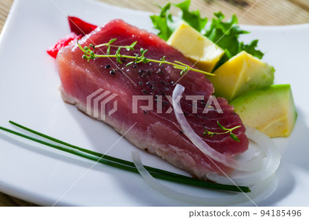 Delicious pieces raw tuna, green avocado and greens at plate 94185496