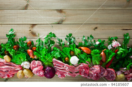 Raw mutton and vegetables assortment on natural wooden background Raw mutton and vegetables assortment on natural wooden background 94185607