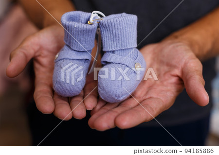 Blue baby shoes on hands of man 94185886