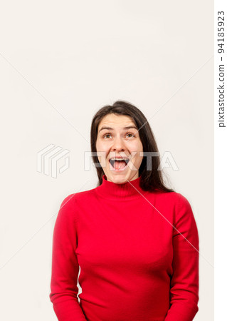 A brunette woman in a red sweater laughs with her mouth open and looks up, a place to text A brunette woman in a red sweater laughs with her mouth open and looks up, a place to text 94185923