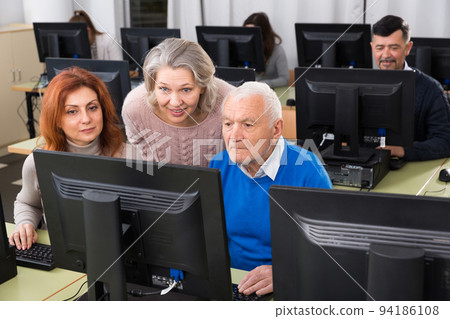 Elderly people working together on computer 94186108