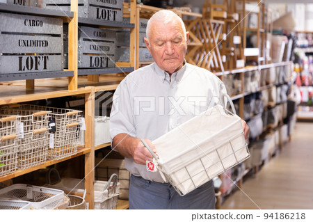 Man pensioner choosing storage basket at store Man pensioner choosing storage basket at store 94186218