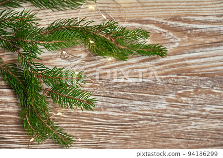 Christmas composition with fir tree branches and lighting garland on wooden background. Christmas frame, flat lay. Xmas greeting banner with copy space Christmas composition with fir tree branches and lighting garland on wooden background. Christmas frame, flat lay. Xmas greeting banner with copy space 94186299