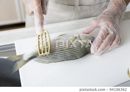 Japanese housewife cooking fish in the kitchen 94186362