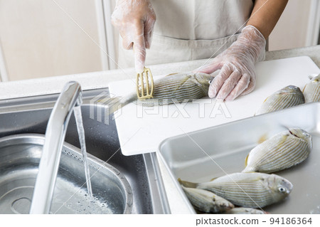 Japanese housewife cooking fish in the kitchen Japanese housewife cooking fish in the kitchen 94186364