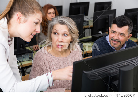 Young female tutor explaining how to use computers 94186507