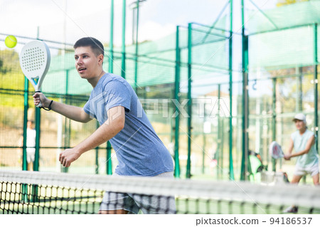 Focused teenager playing friendly paddleball match on outdoor court Focused teenager playing friendly paddleball match on outdoor court 94186537