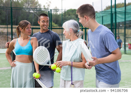 Different aged men and women talking after padel tennis match 94186706