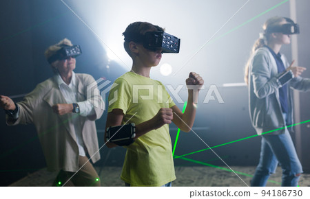 Boy in VR headset playing games with his family Boy in VR headset playing games with his family 94186730