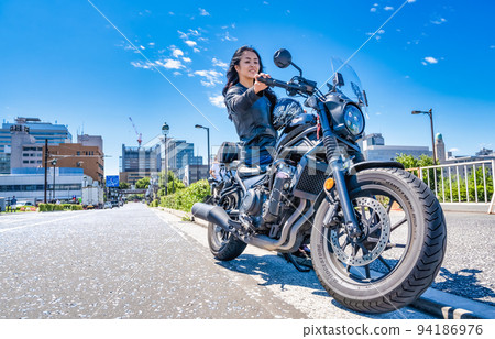 A female rider touring Yokohama on a large cruiser bike 94186976
