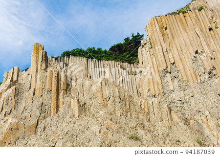 high coastal cliff made of columnar granite, landscape on the island of Kunashir high coastal cliff made of columnar granite, landscape on the island of Kunashir 94187039