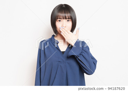 A young woman who hides her mouth with her hand and makes a secret pose A young woman who hides her mouth with her hand and makes a secret pose 94187620