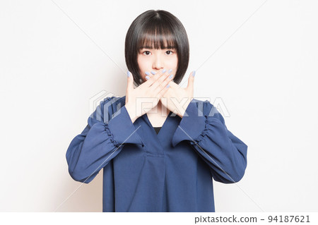 A young woman who hides her mouth with her hand and makes a secret pose A young woman who hides her mouth with her hand and makes a secret pose 94187621