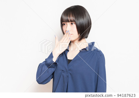 A young woman who hides her mouth with her hand and makes a secret pose A young woman who hides her mouth with her hand and makes a secret pose 94187623