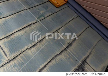 The faded and dirty roof of a 25-year-old detached house 94189064