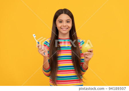 Happy kid hold toothbrush and apple yellow background, dental health 94189307