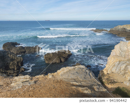 View of empty Praia Selvagem sand beach with ocean waves and sharp rock and cllifs at wild Rota Vicentina coast near Porto Covo, Portugal. 94190442