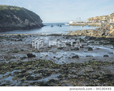 Rocky sea shore at wild Vicentina coast in Porto Covo with groups of fishermans boats anchored in a calm bay 94190449