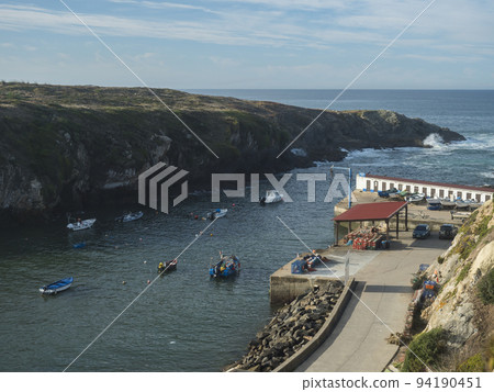 Rocky sea shore at wild Vicentina coast in Porto Covo with groups of fishermans boats anchored in a calm bay 94190451