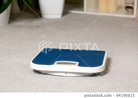 Blue floor scales on the gray carpet in the room. The idea of losing weight and controlling a person's weight Blue floor scales on the gray carpet in the room. The idea of losing weight and controlling a person's weight 94190815