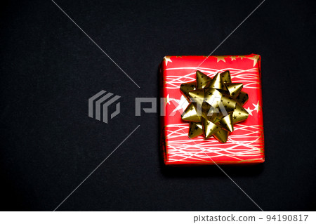 Red gift box with a golden bow on a black background with a place for text Red gift box with a golden bow on a black background with a place for text 94190817