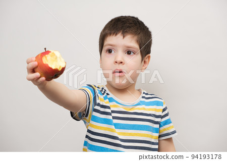 A 4 year old boy eats a red apple and squirms. The child does not like fruit 94193178